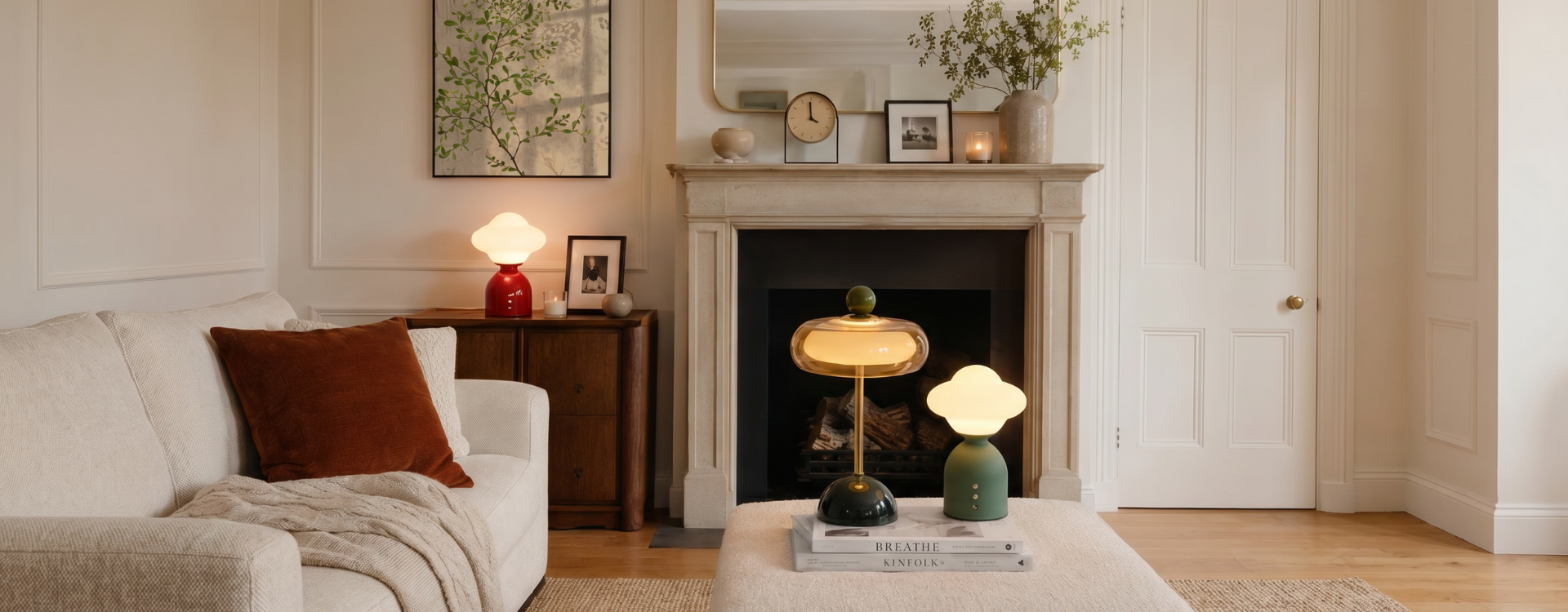 Soft summer living room with warm portable lamps, neutral sofa, wall art, mirror and cosy layered décor for relaxed evening lighting.