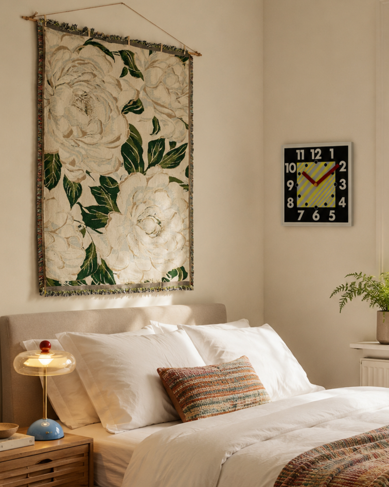 Large floral textile wall art with cream flowers and green leaves styled above a cosy UK bedroom, adding soft botanical texture and warm decorative detail.