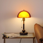Vintage-style table lamp with a warm glow on a glass table next to a sofa.