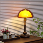 Vintage-style table lamp with a yellow glass shade on a wooden surface.