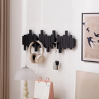 Black wall-mounted hook holder with headphones and keys on a white wall in bedroom