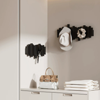 Wall-mounted black coat black rack with a hat, bag, and folded clothes in a bedroom room setting.