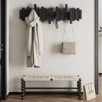 Wall-mounted coat black rack with hooks holding a coat and handbag, next to a bench and shopping bag at the hallway