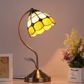 Classic Tiffany-style table lamp with bronze curved stand and stained glass shade in yellow and white tones, elegant vintage lighting for bedrooms, living rooms, or reading corners