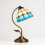 Retro Tiffany-style lamp with blue glass accents, curved bronze stand, stylish lighting