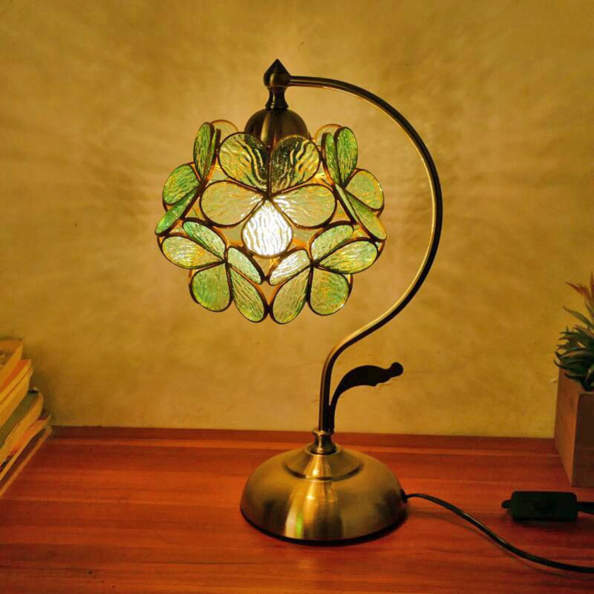 Aqua Petal Glow Lamp glowing warmly on a wooden desk, showcasing green-aqua stained glass petals and elegant brass stand — KaShi Living home décor lighting