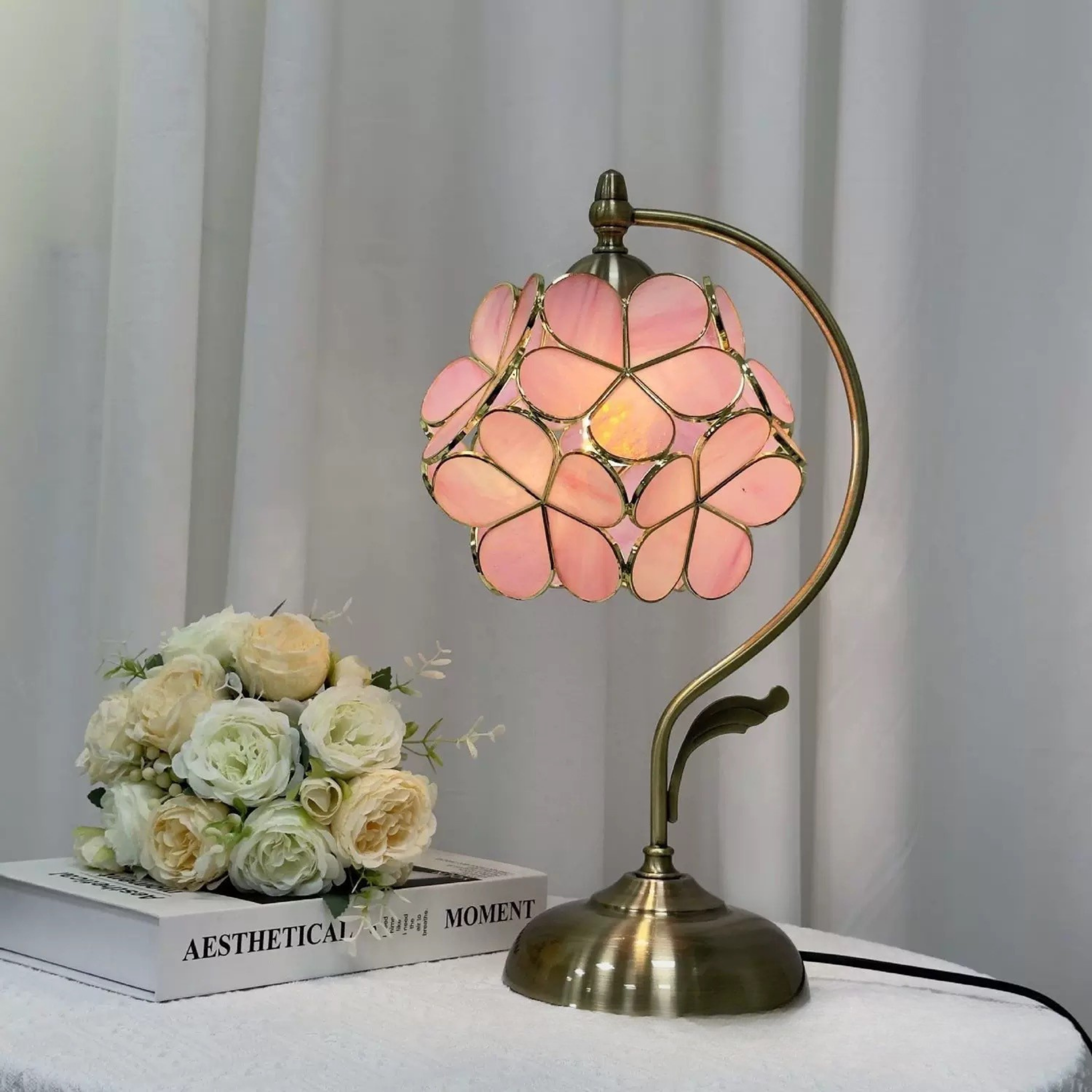 Blush Petal Glow Lamp by KaShi Living — pink stained glass table lamp with brass base, styled beside white roses for a soft daylight look