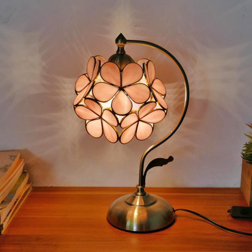 Blush Petal Glow Lamp illuminated on a wooden desk, featuring soft pink stained glass petals and brass curve stand — elegant home lighting by KaShi Living