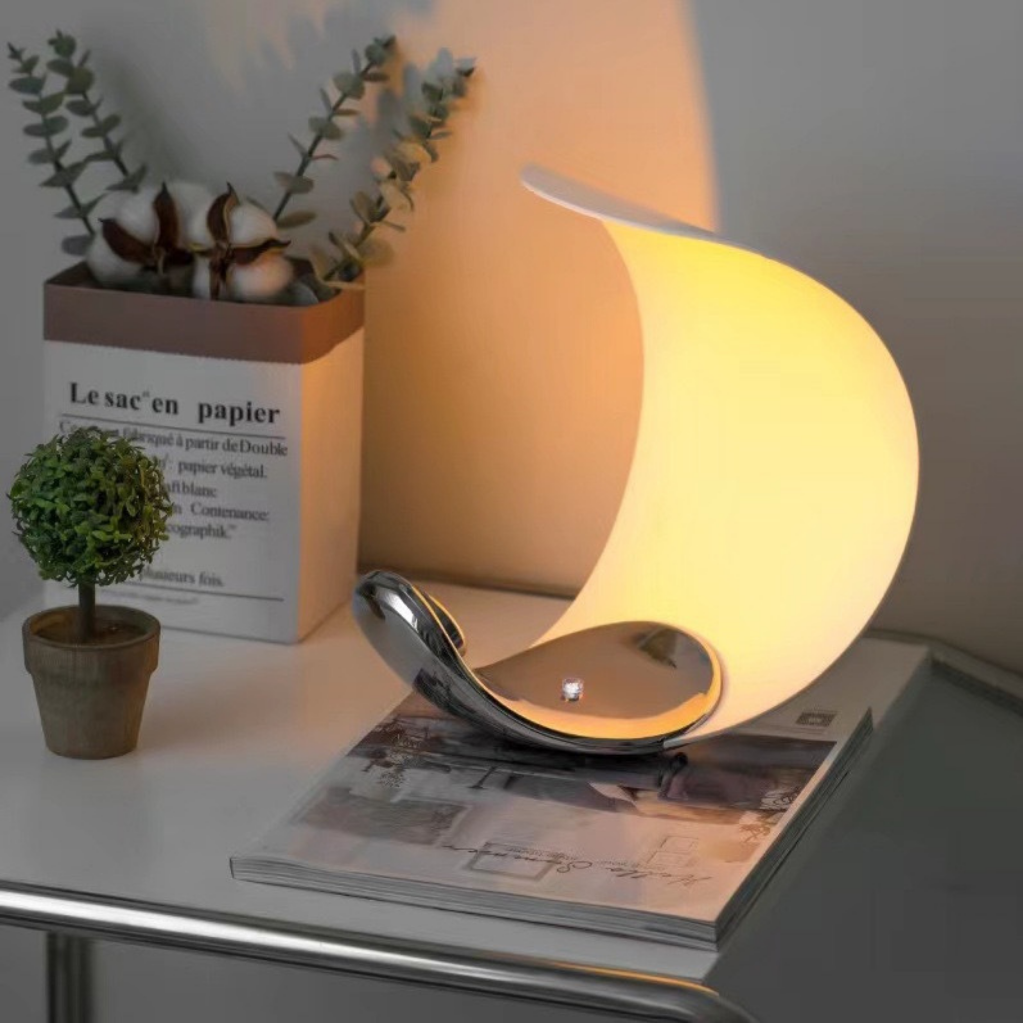 Eclipse Arc Lamp emitting golden light — sculptural crescent design on white table, perfect for cosy home settings, KaShi Living