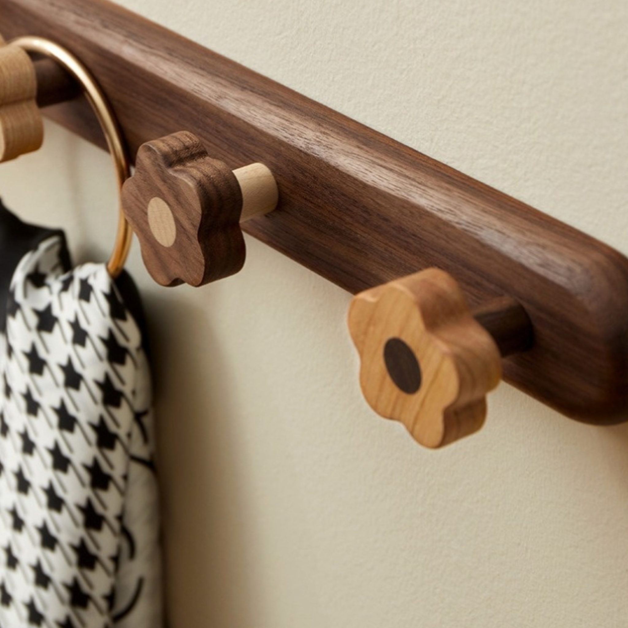 Wooden coat rack with decorative hooks on a neutral wall.