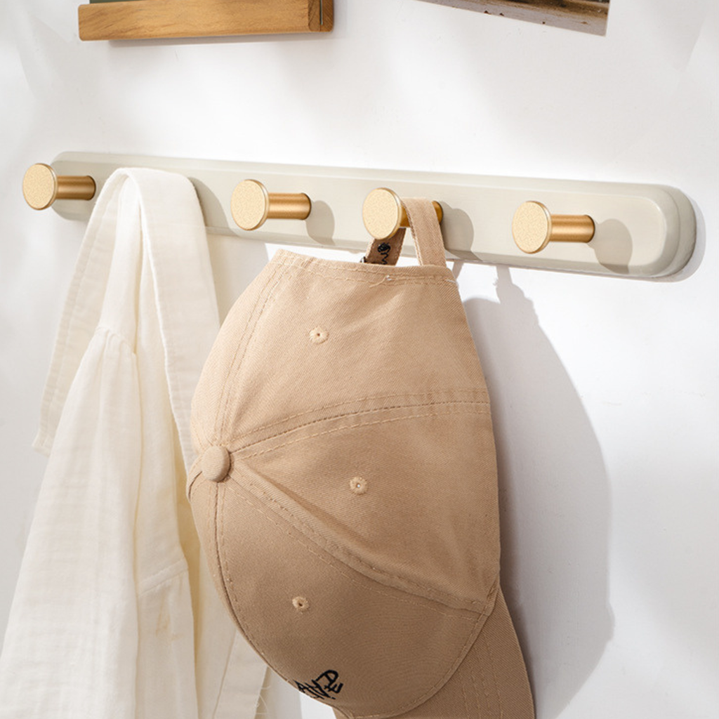 A warm cream-effect wall hook rack with gold-tone pegs for coats, bags, keys and everyday hallway organisation.