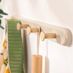 Wall-mounted hook with wooden hooks holding a green towel and other items.