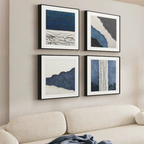 Set of four blue, navy, ivory and charcoal abstract framed wall art prints displayed above a cream sofa in a modern neutral living room by KaShi Living.