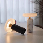 The Elara Disc Portable Table Lamp is a rechargeable accent lamp with a broad rounded shade and cylindrical stone-effect base for bedrooms, desks and cosy living spaces.
