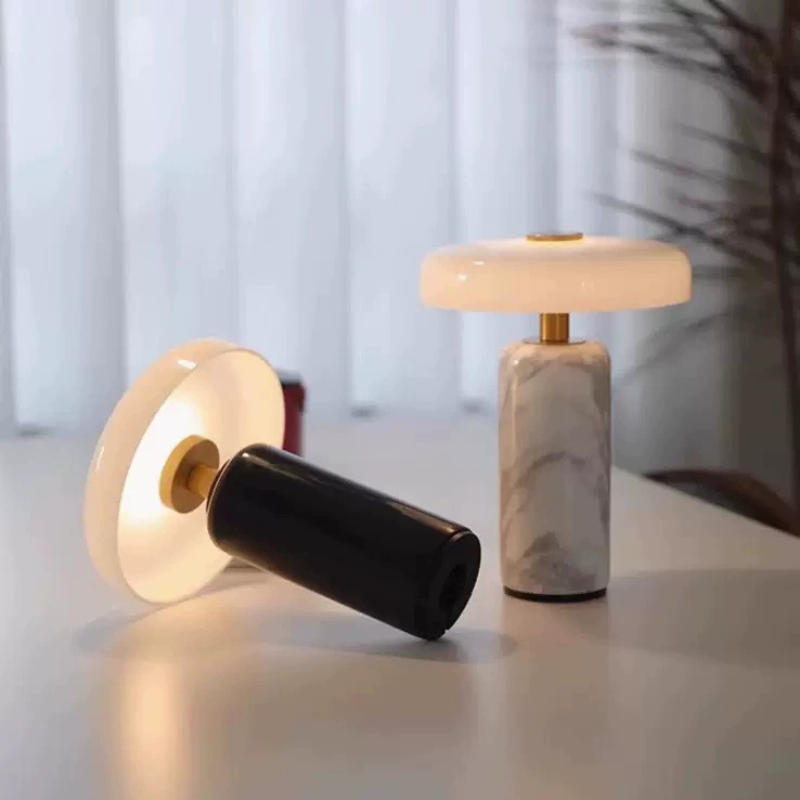The Elara Disc Portable Table Lamp is a rechargeable accent lamp with a broad rounded shade and cylindrical stone-effect base for bedrooms, desks and cosy living spaces.