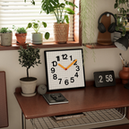 A square decorative wall clock with a grid-style face, bold scattered numbers and yellow hands, ideal for UK bedrooms, living rooms, kitchens and home offices.