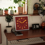 A square checkerboard wall clock with warm red, navy and cream details, suited to UK kitchens, bedrooms, living rooms and playful gallery walls.