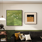 Sage Flight green bird artwork and Harvest Pumpkin framed wall art displayed above a black sofa in a warm UK living room.