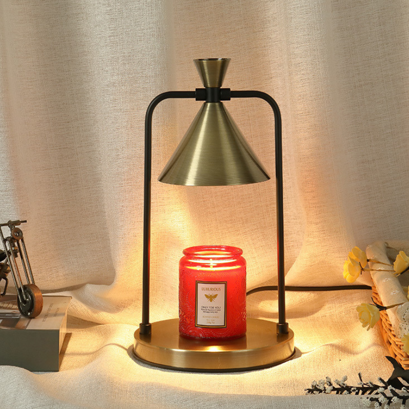 Sienna Antique Gold Cone Candle Warmer Lamp with a brushed gold shade, gold base and black frame, warming a red jar candle.
