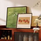 Sage Flight and Persimmon Parade framed wall art displayed on a warm wooden console cabinet in a cosy living room by KaShi Living.