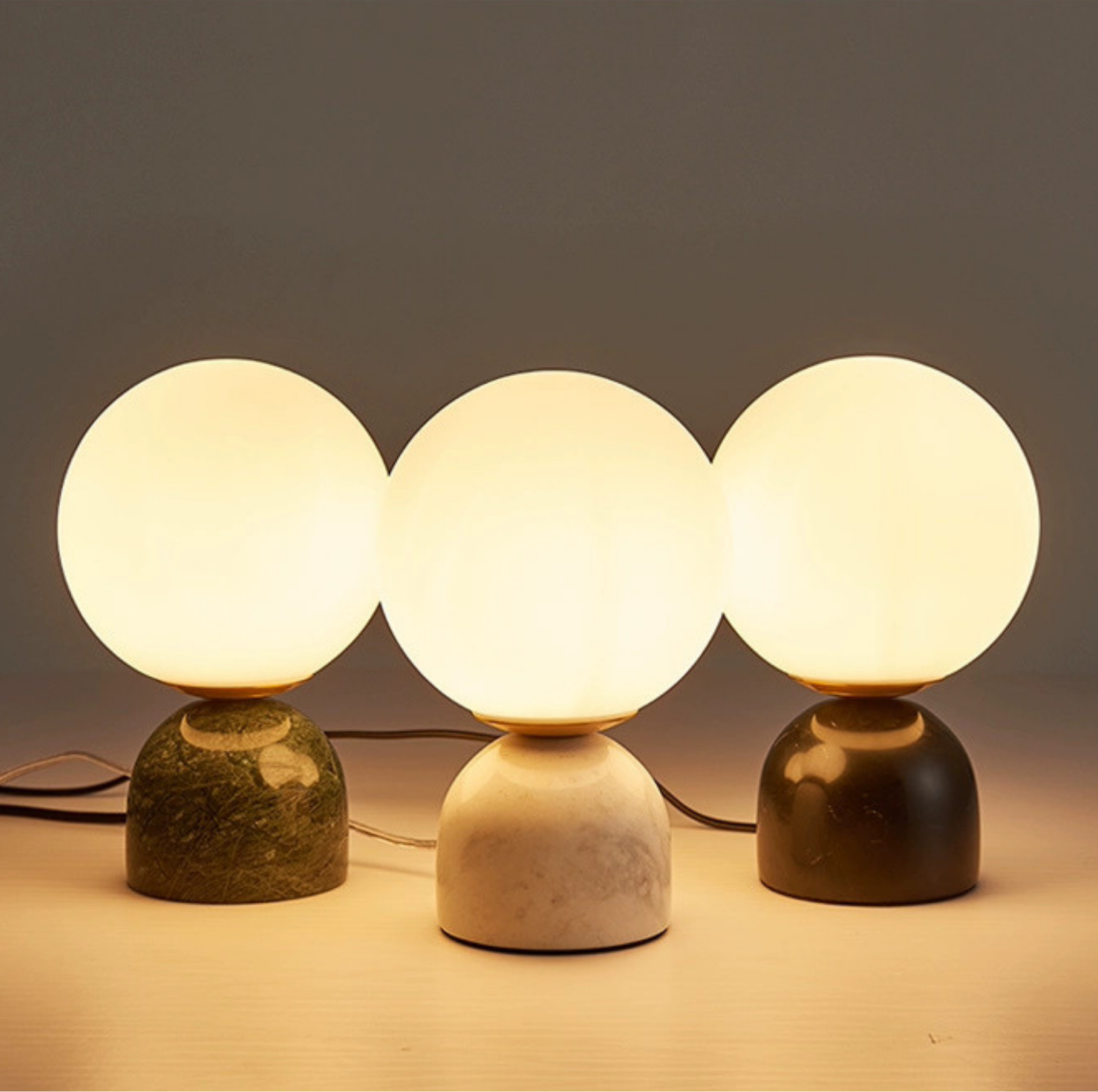 Luna Stone Lamp trio illuminated — glowing frosted globes on marble bases in green, white, and black, ambient night lighting by KaShi Living
